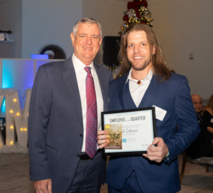 Josh Calhoun with BCC CEO Blake Gable at company holiday party, standing with certificate award.